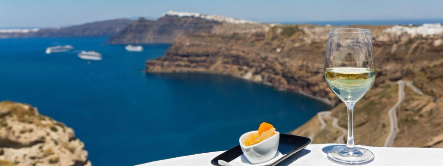 A glass of white wine, delectable bites on a plate, complemented by a captivating view. Savoring flavors, embracing beauty.